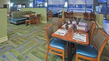A dining area with tables set for four, chairs, and a patterned carpet.