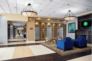 A hotel lobby with a check-in counter, seating area, and a reception desk.