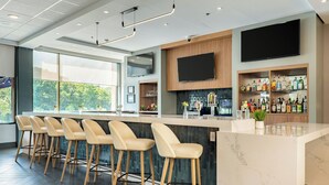 Une cuisine moderne avec un coin bar, des tabourets de bar, un grand téléviseur et un présentoir pour les vins et les spiritueux.
