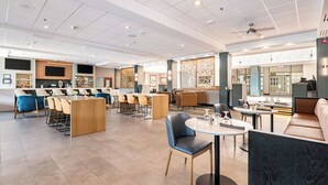 Un restaurant moderne doté d’un bar, de différents types de tables et offrant une vue sur l’extérieur.