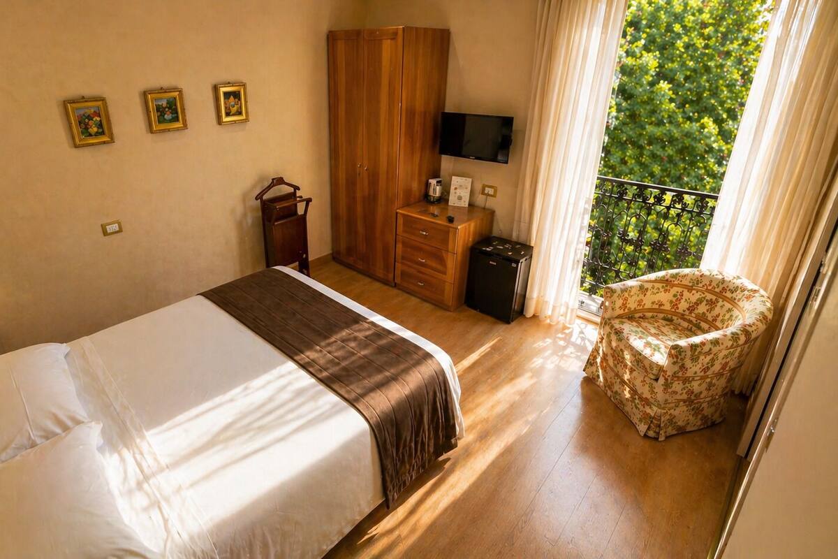 A hotel room with a bed, a wardrobe, a television, a small table, and a chair.