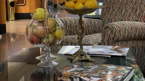 A lobby area with a glass coffee table displaying fruits, a book, and a decorative item. - NSM Hotel Cicolella (Foggia)
