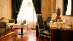 A room with a dining table, a sofa, a chair, a lamp, and a fruit display. - NSM Hotel Cicolella (Foggia)