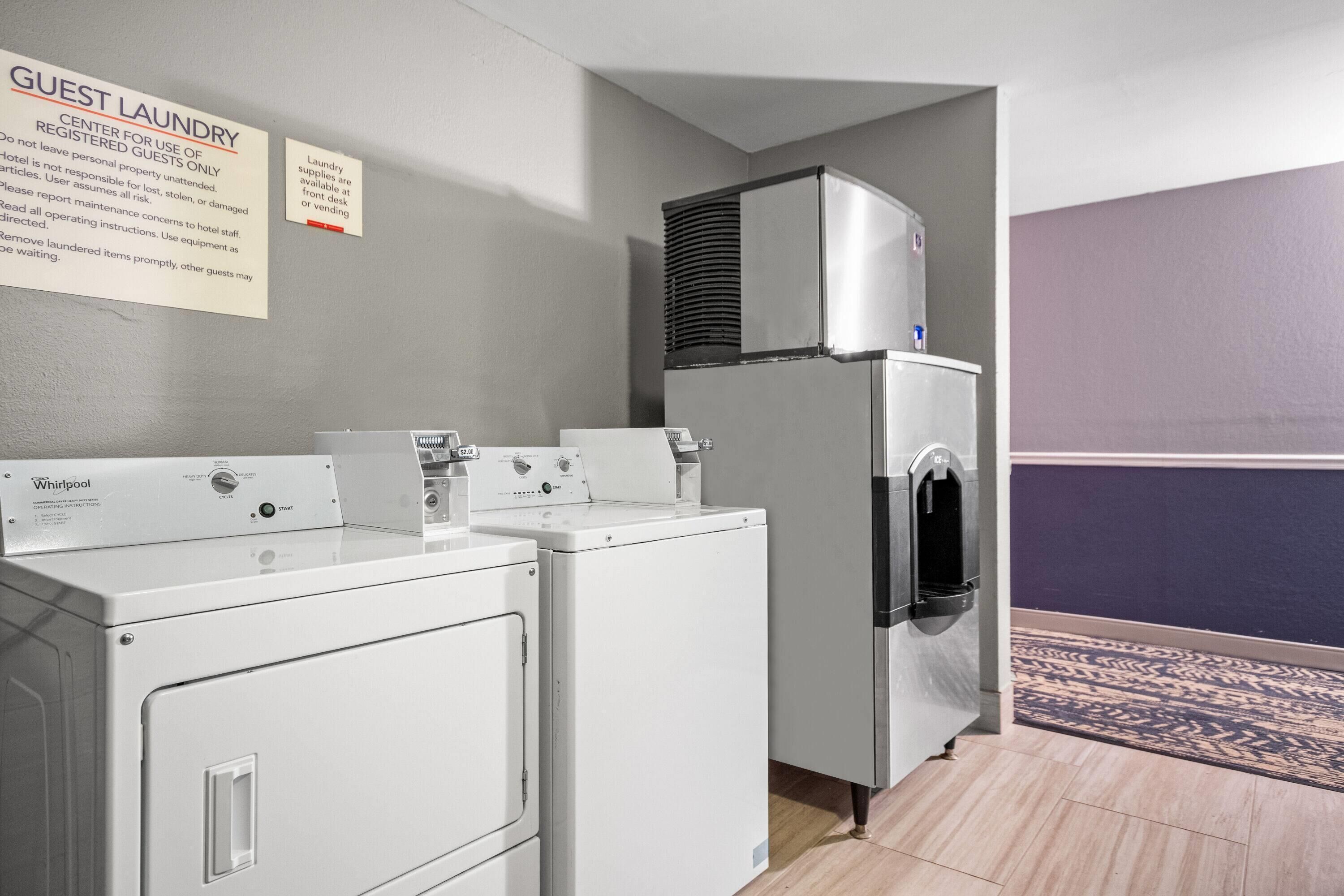A laundry area with Whirlpool washers and dryers, a refrigerator, and a sign indicating it's for registered guests only.
