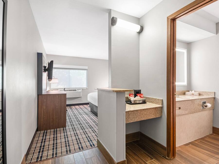 A modern hotel bathroom with a wooden vanity, a toilet, and a shower area.