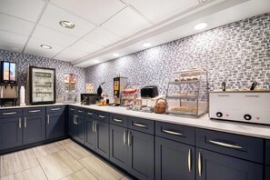 Een moderne keuken met donkere kastjes, een wit aanrechtblad en diverse apparaten, waaronder een koffiezetapparaat en een broodrooster.