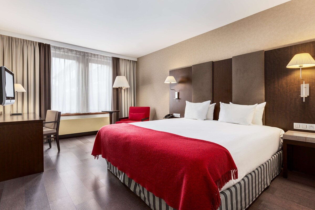 Una habitación de hotel con una cama grande, un escritorio, una silla y un televisor.