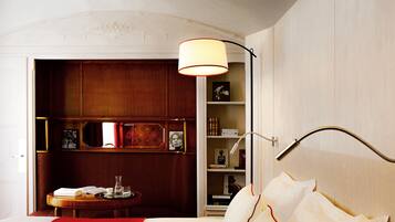 Une chambre d’hôtel avec un grand lit, une table de chevet, une lampe et une vue sur un meuble en bois doté d’étagères.