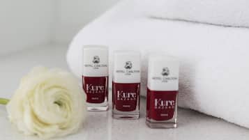 Drei Flaschen Hotel Carlton Lyon Kure Bazaar Paris Nagellack, eine weiße Rose und ein weißes Handtuch.