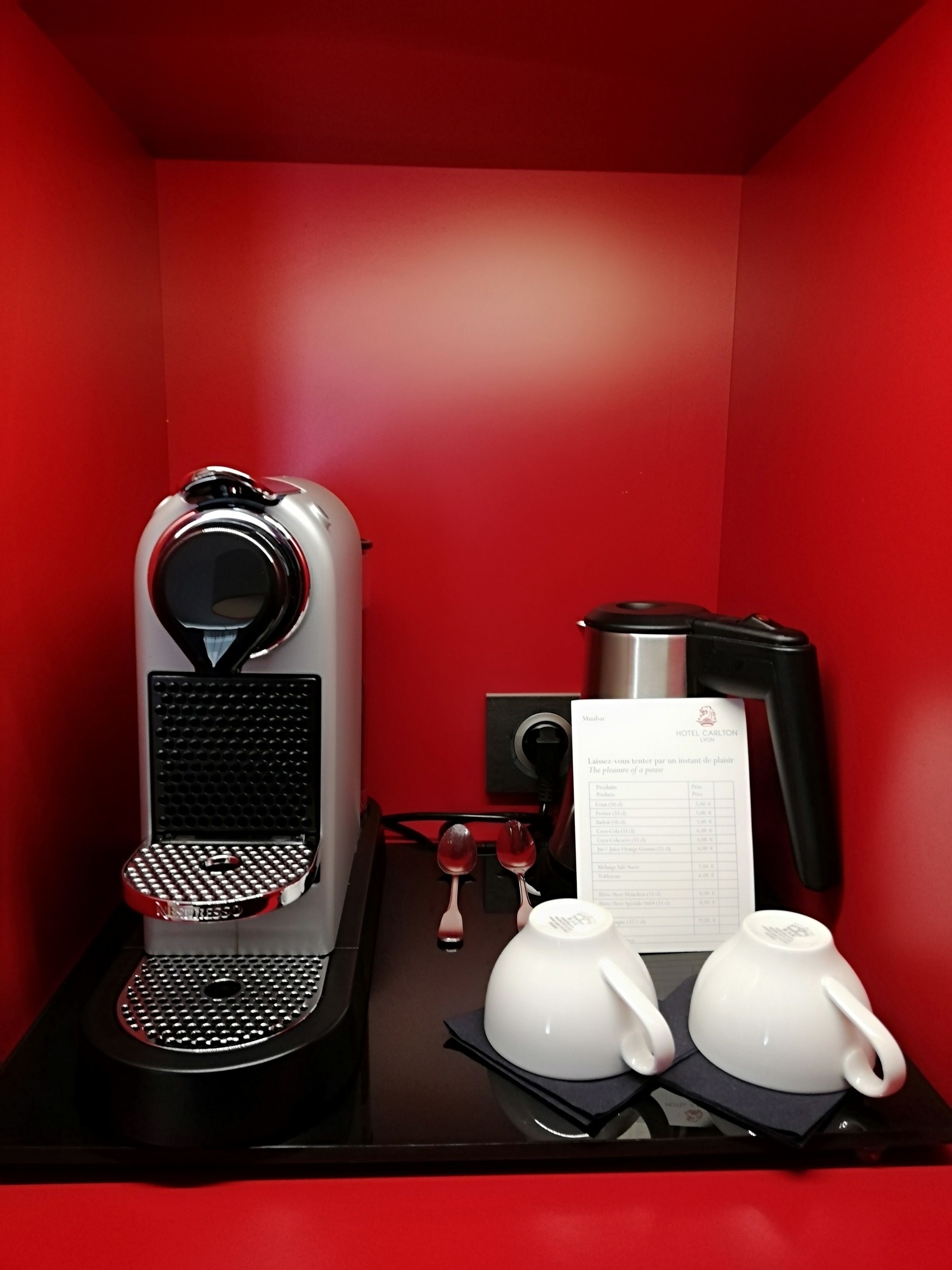 A compact coffee station with a coffee machine, a menu, and two teapots on a tray.