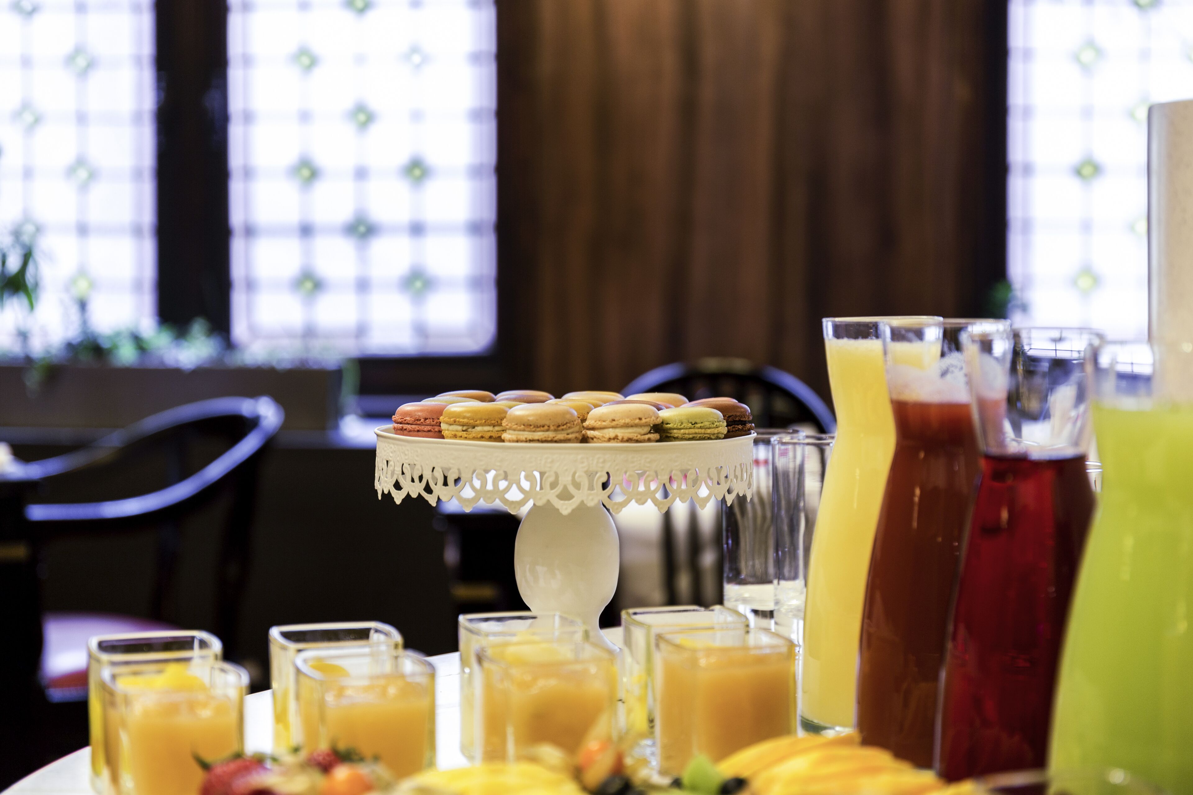 A breakfast buffet with macarons, fruit, and various beverages.
