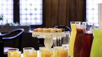 A breakfast buffet with macarons, fruit, and various beverages.