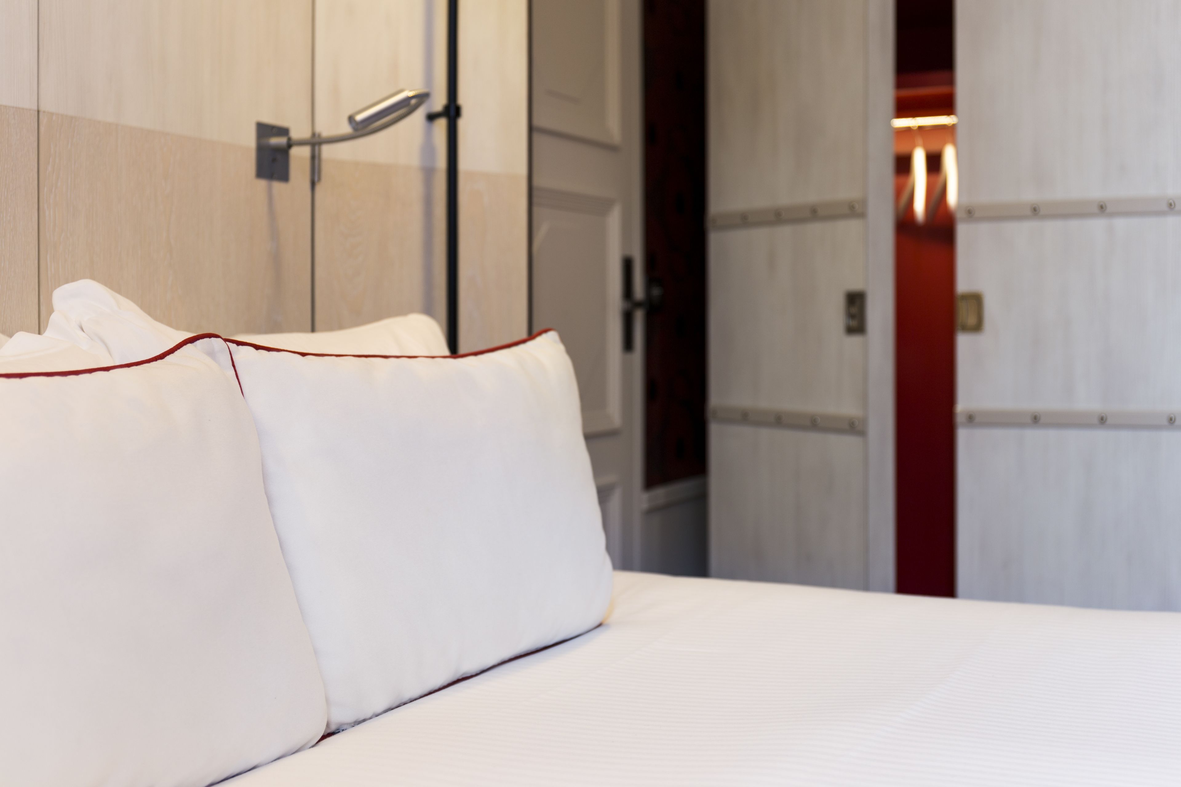 Ein Hotelzimmer mit einem Bett, Kissen und einer Tür zu einem anderen Raum.