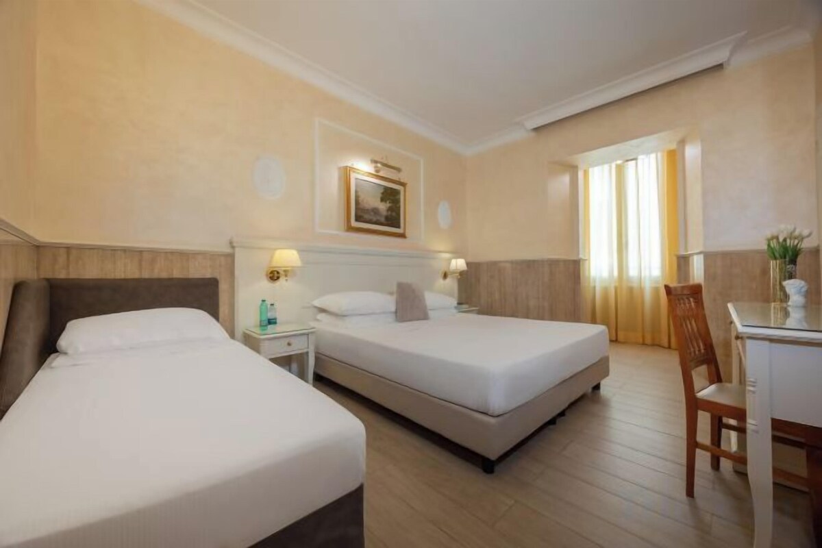 Una habitación de hotel con dos camas, un escritorio y una silla.