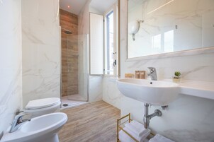 A modern bathroom with a marble sink, a toilet, and a shower.