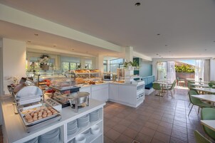A modern breakfast area with buffet counters, seating, and large windows.