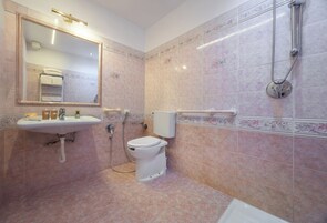 Et badeværelse med vask, toilet og bruser.