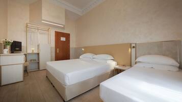 A hotel room with two beds, a desk, a TV, and a wardrobe.