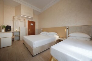 Habitación de hotel con dos camas, un escritorio, un televisor y un armario.