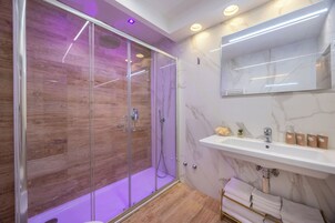 Un bagno moderno con cabina doccia in vetro, lavabo in marmo e pavimento in legno.