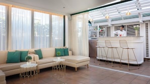 A modern living area with a sofa, a round coffee table, and a bar area with stools. - Hotel Palladium Palace (Rome)