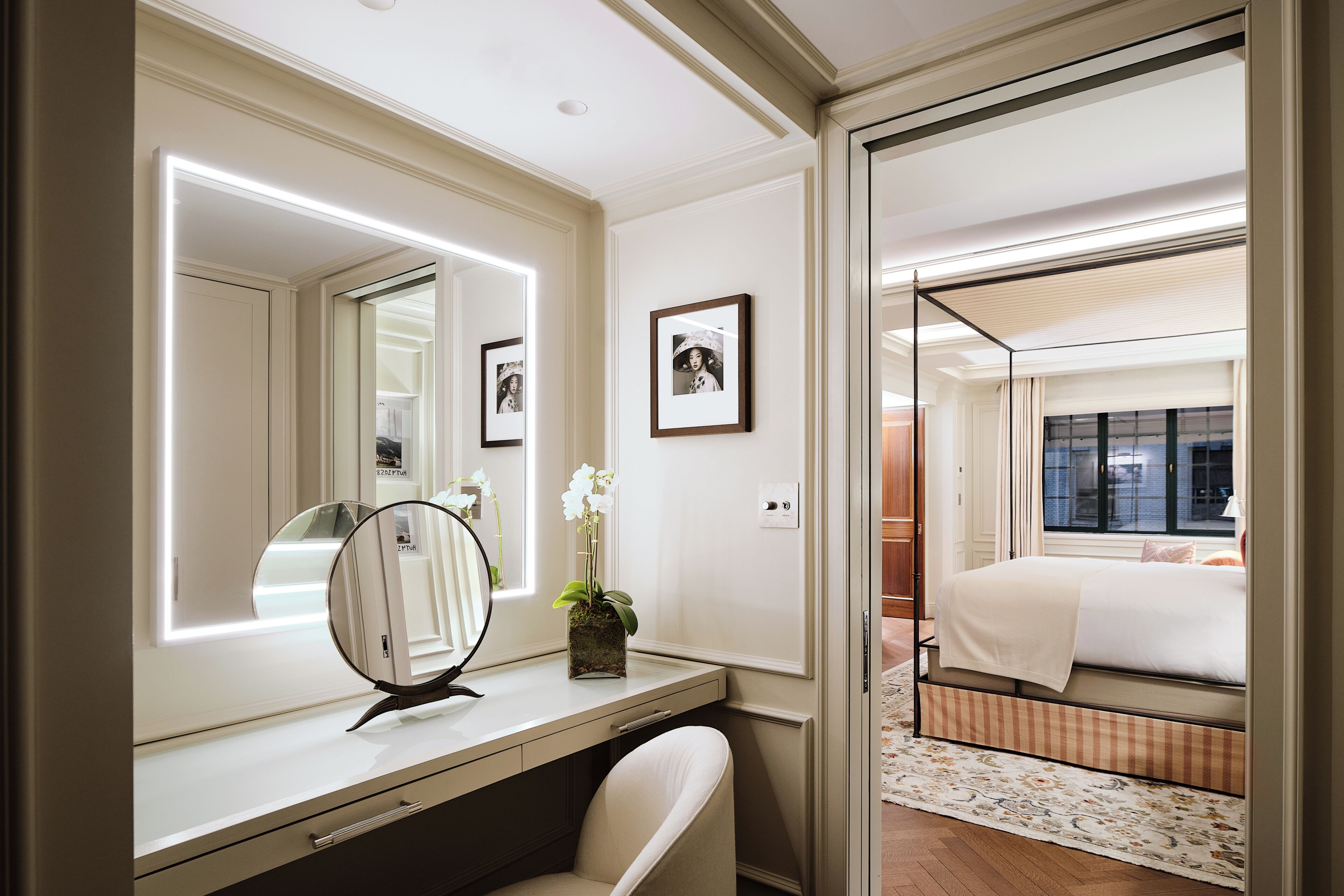 A hotel room with a vanity, a bed, a window, and a mirror.