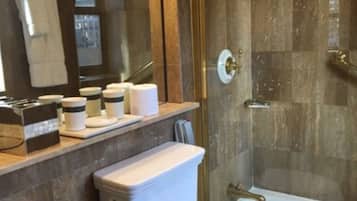 A modern bathroom with a marble sink, a toilet, and a glass-enclosed shower.