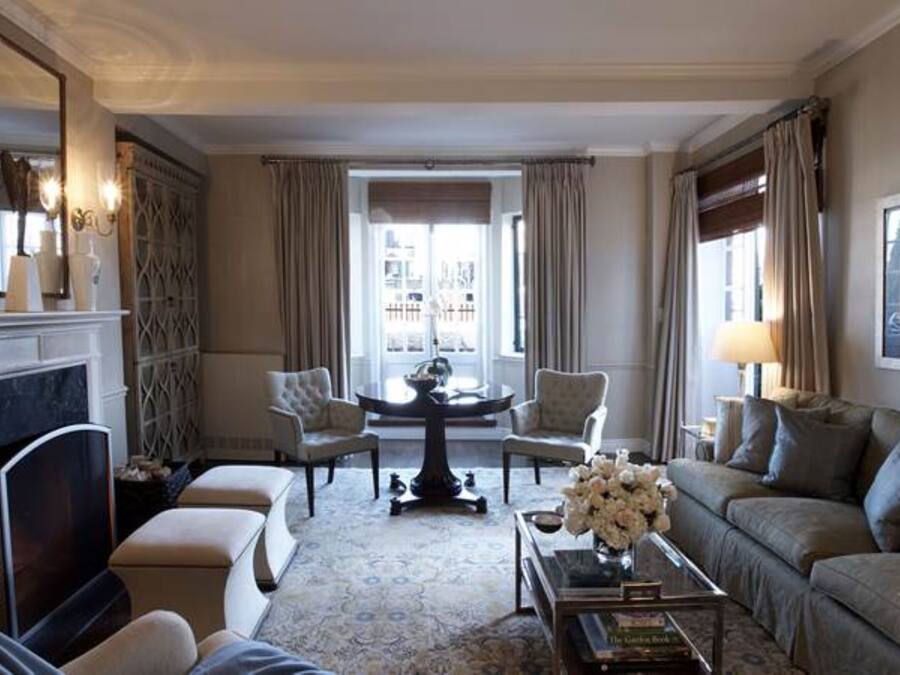 A cozy living room with a fireplace, comfortable seating, and a view through a large window.
