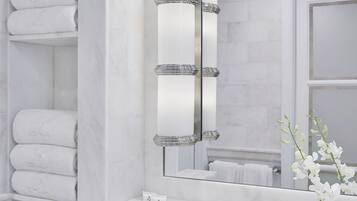Un baño moderno con un lavabo de mármol, un espejo grande con luces y toallas ordenadas.