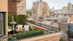 Terraço no telhado com vista para edifícios da cidade, um pequeno jardim e área de estar ao ar livre.