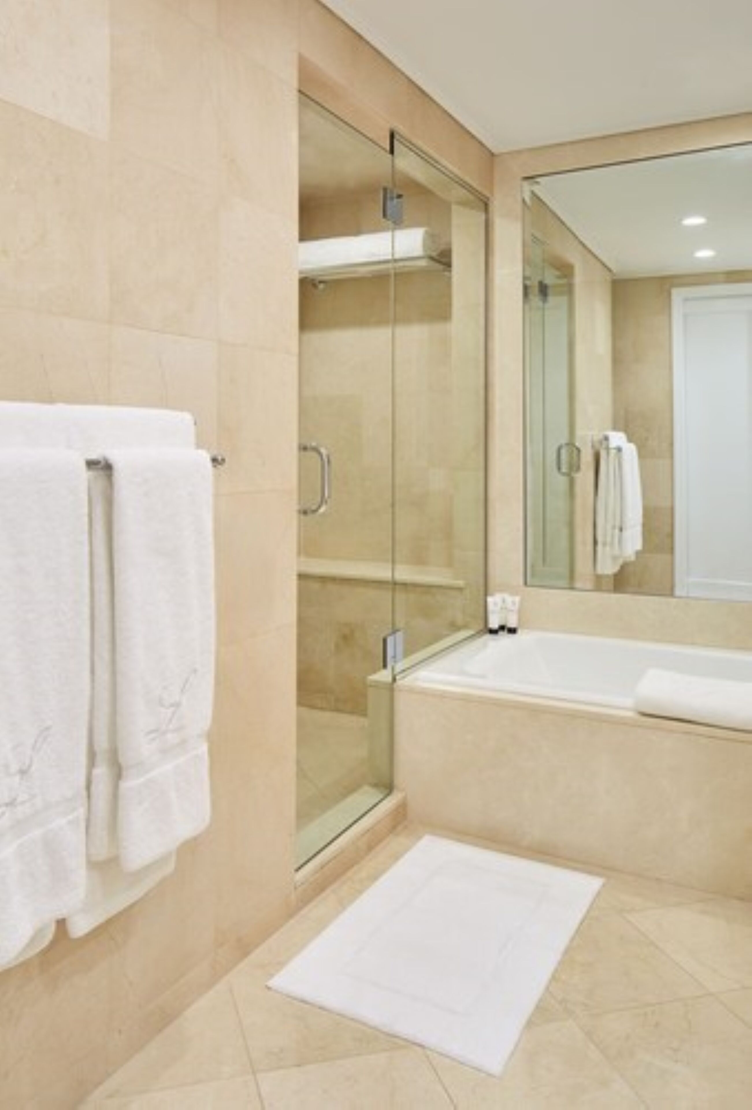 Un baño moderno con ducha de vidrio, un espejo grande y una bañera.