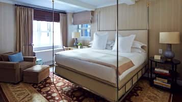 A hotel room with a large bed, a sofa, a small table, and a bookshelf.