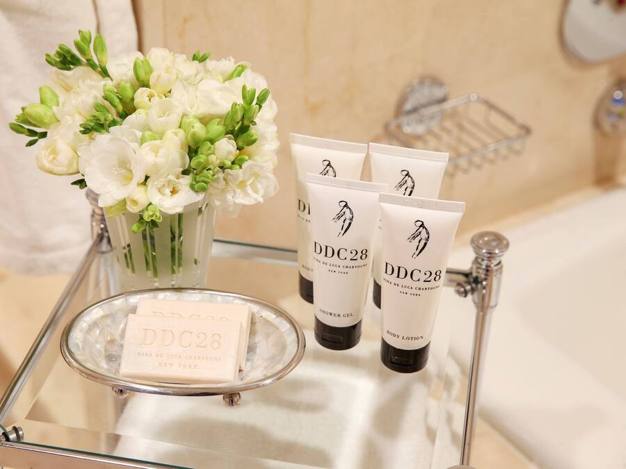 A bathroom vanity with a glass tray holding a bar of soap and three tubes of DDC28 body lotion.