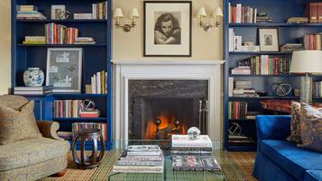 A living room with a fireplace, bookshelves, a sofa, and a coffee table with books.