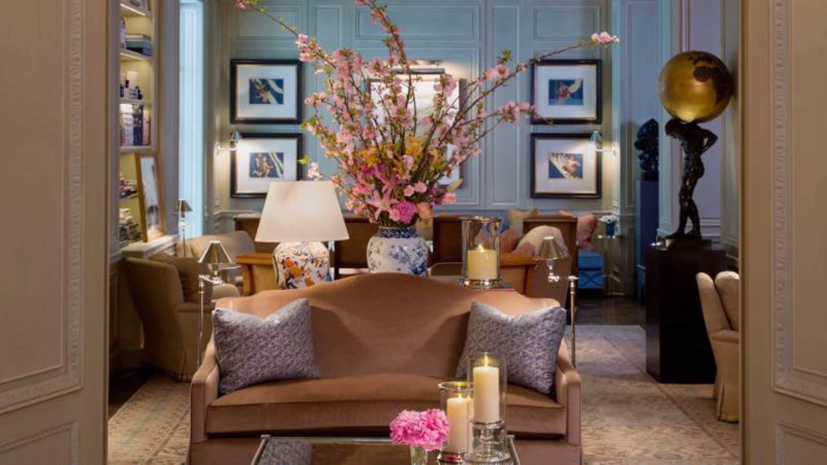 Un soggiorno elegante con un divano marrone, cuscini decorativi, un vaso con fiori e quadri appesi alle pareti.