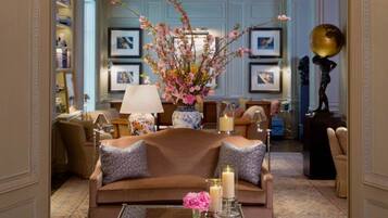 Un soggiorno elegante con un divano marrone, cuscini decorativi, un vaso con fiori e quadri appesi alle pareti.
