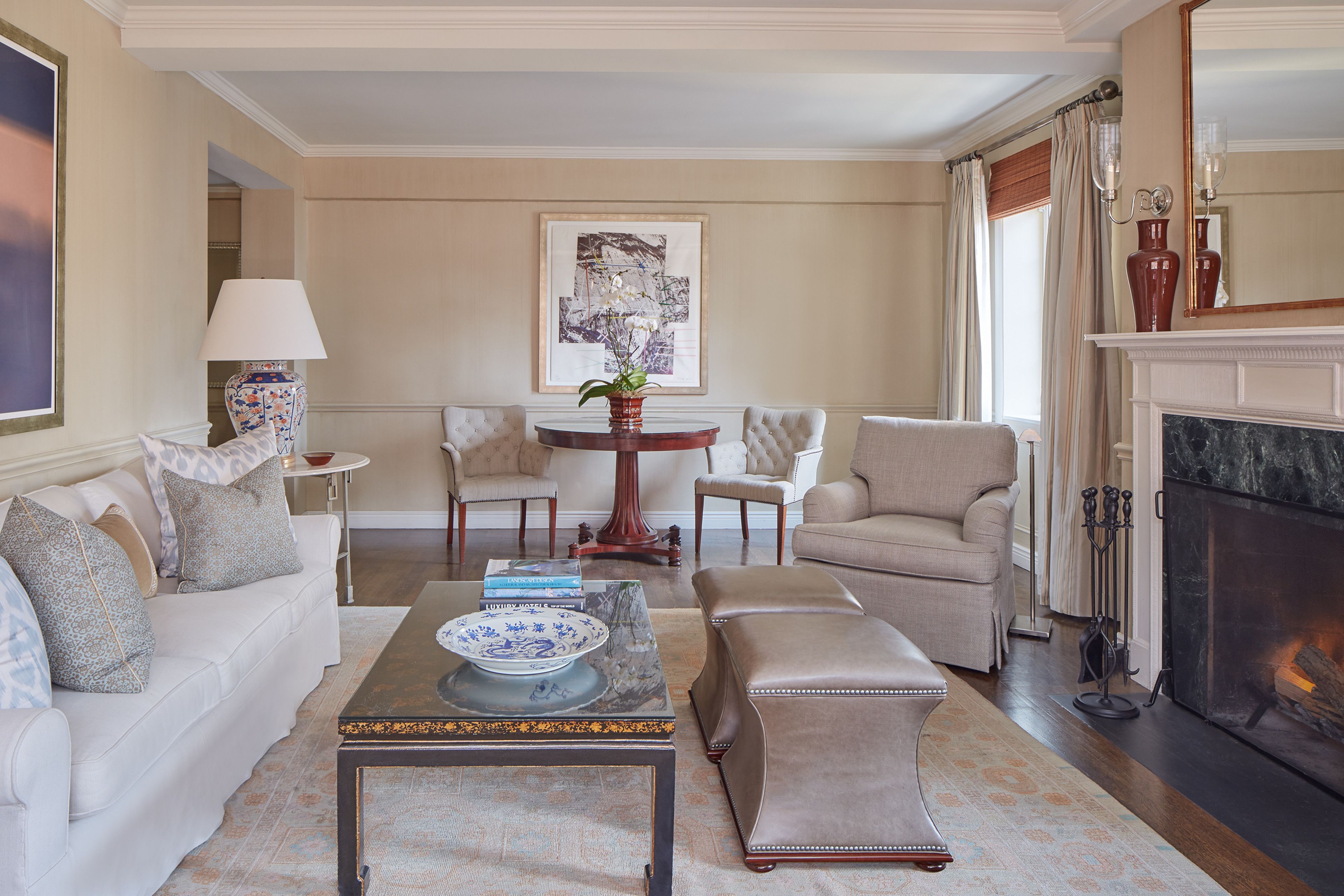 A living room with a white sofa, beige armchairs, a coffee table, and a fireplace.