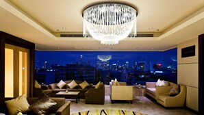 Una sala de estar moderna con vistas a la ciudad, un candelabro y varios sofás y sillones.