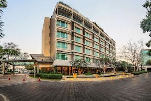 Un hotel de varios pisos con un diseño moderno, que cuenta con una entrada cubierta y un área exterior ajardinada.