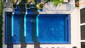 Una amplia piscina exterior con diseño de azulejos, rodeada de sillones de descanso y una pequeña mesa.