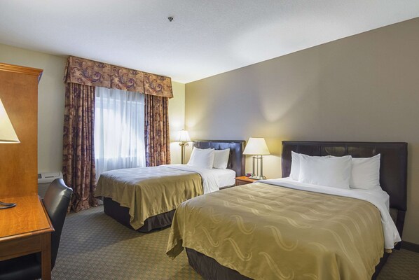 A hotel room with two beds, a desk, and a chair. - Quality Inn Fresno Yosemite Airport (Fresno)