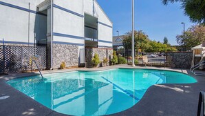 A swimming pool with a stone wall and a metal fence. - Quality Inn Fresno Yosemite Airport (Fresno)