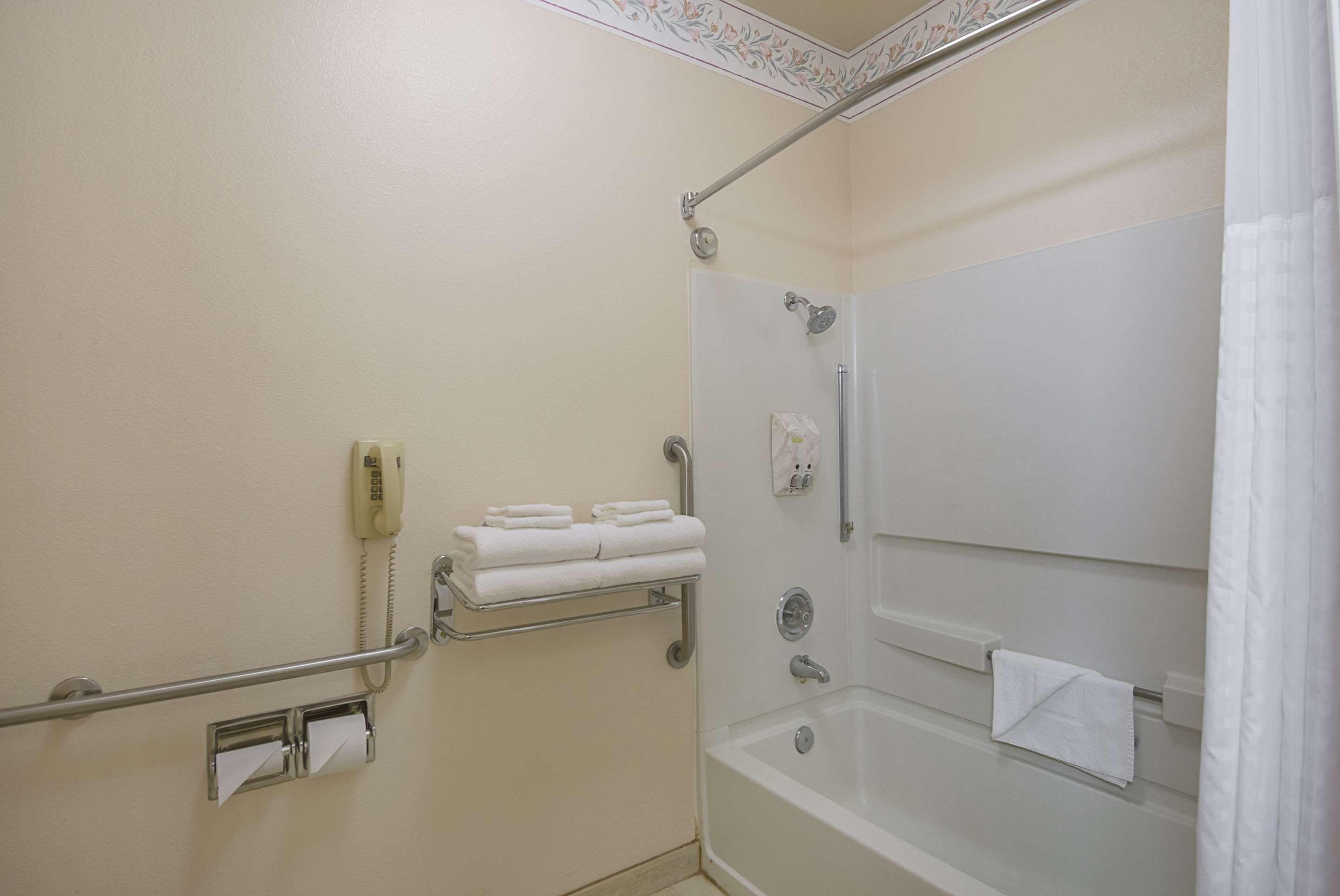 A bathroom with a shower, a toilet, a sink, and a telephone.