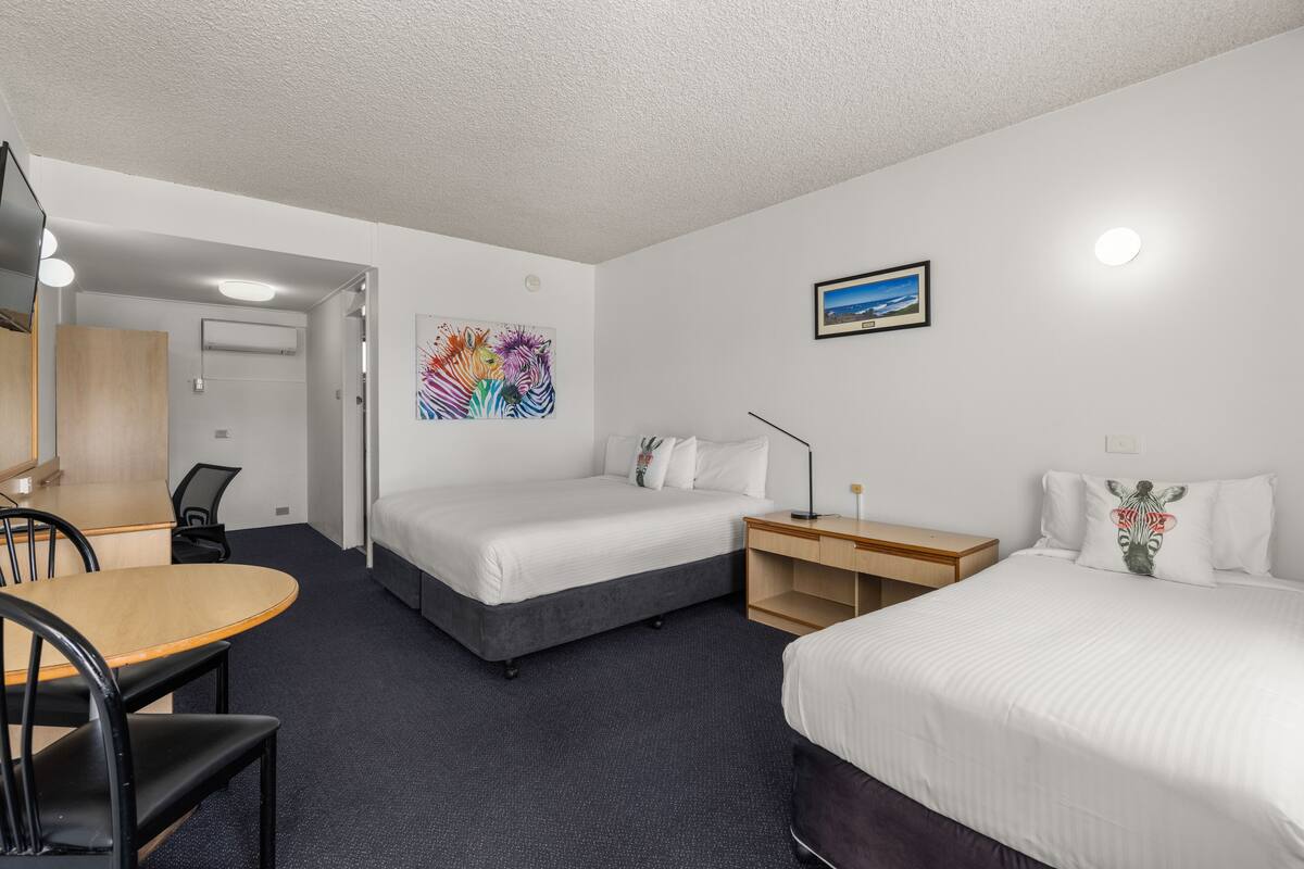 Une chambre d’hôtel avec deux lits, un bureau et une chaise.