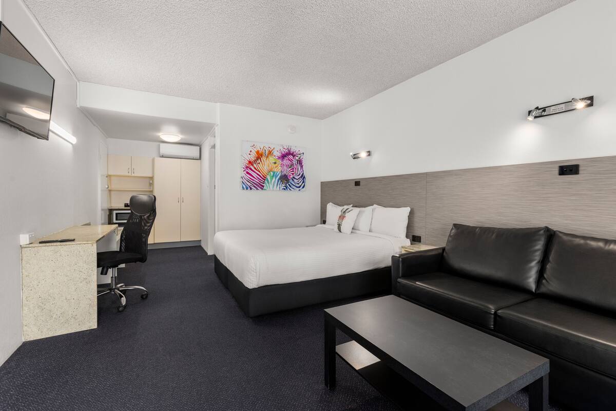 Une chambre d’hôtel moderne équipée d’un lit, d’un bureau, d’un canapé et d’une table basse.