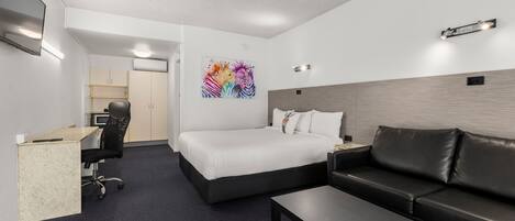 A modern hotel room with a bed, a desk, a sofa, and a coffee table.