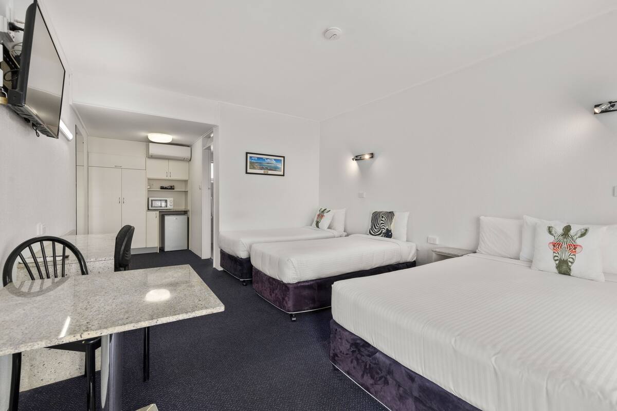 Une chambre d’hôtel comprenant un lit, un bureau, une chaise, une petite kitchenette et une salle de bain.