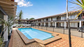 Una piscina al aire libre, sillones reclinables de piscina