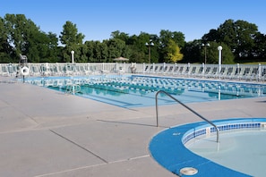 Una piscina con varias pistas de natación, un puesto de socorrista y un área cercada con sillas de descanso.