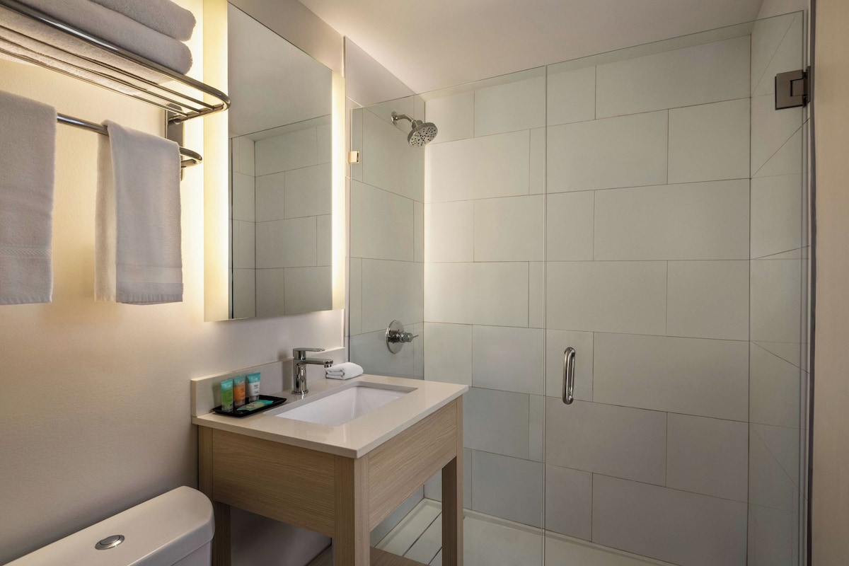 A modern bathroom with a sink, mirror, and shower.
